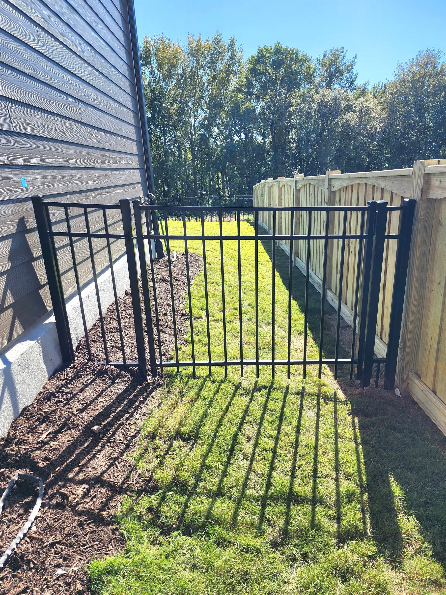 Black aluminum gate tying into a wood privacy run.