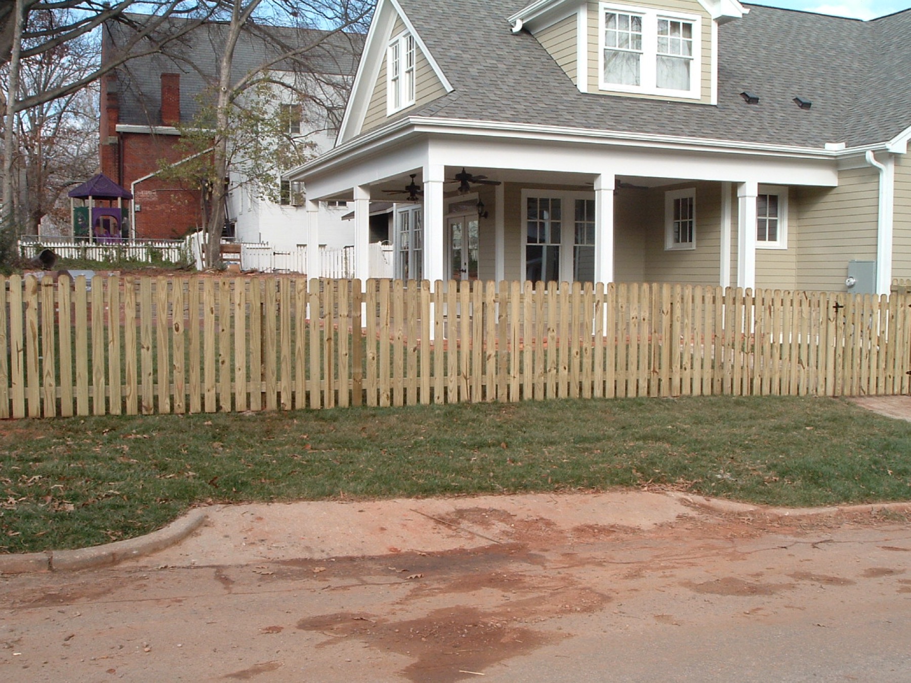 Front-yard wood picket fence framing a classic porch home.